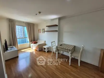 Spacious living room with wooden flooring and large window offering city views.