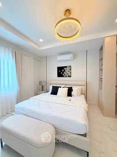 Luxurious bedroom with elegant chandelier and modern decor, featuring a cozy bed and stylish furnishings.