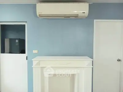 Modern interior with air conditioning and elegant white mantelpiece against blue wall.