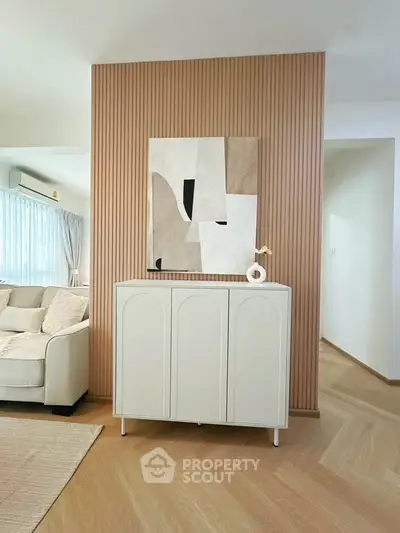 Modern living room with stylish decor and elegant furniture, featuring a chic cabinet and abstract wall art.