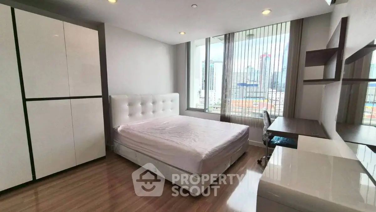 Spacious bedroom with city view, modern furniture, and ample natural light.