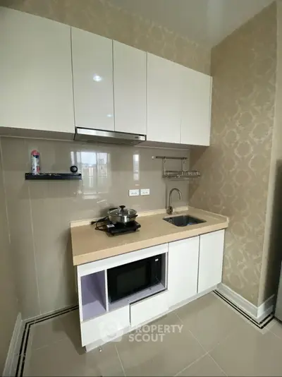 Modern compact kitchen with sleek cabinetry and built-in appliances in a stylish apartment.