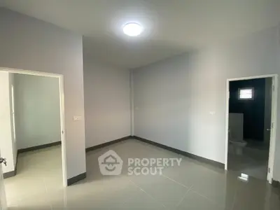 Spacious empty room with glossy tiled floor and two doorways, ideal for customization.