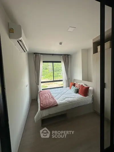 Cozy bedroom with large window and scenic view, modern decor and ample natural light.