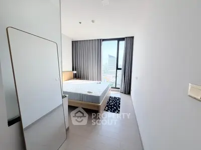 Modern bedroom with large window and city view, featuring minimalist decor and natural light.