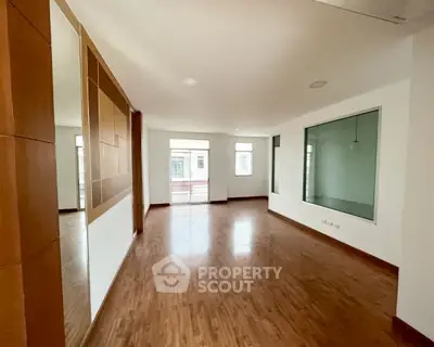 Spacious empty living room with wooden flooring and large windows for natural light.