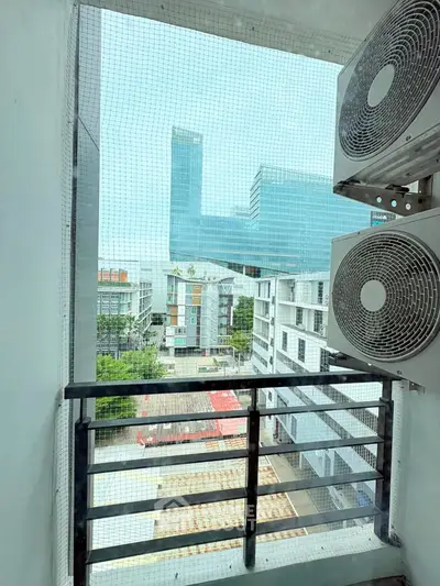Modern urban view from a balcony with air conditioning units, showcasing cityscape and contemporary architecture.