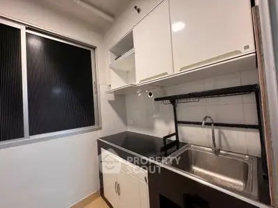 Compact kitchen with sleek black countertop and stainless steel sink
