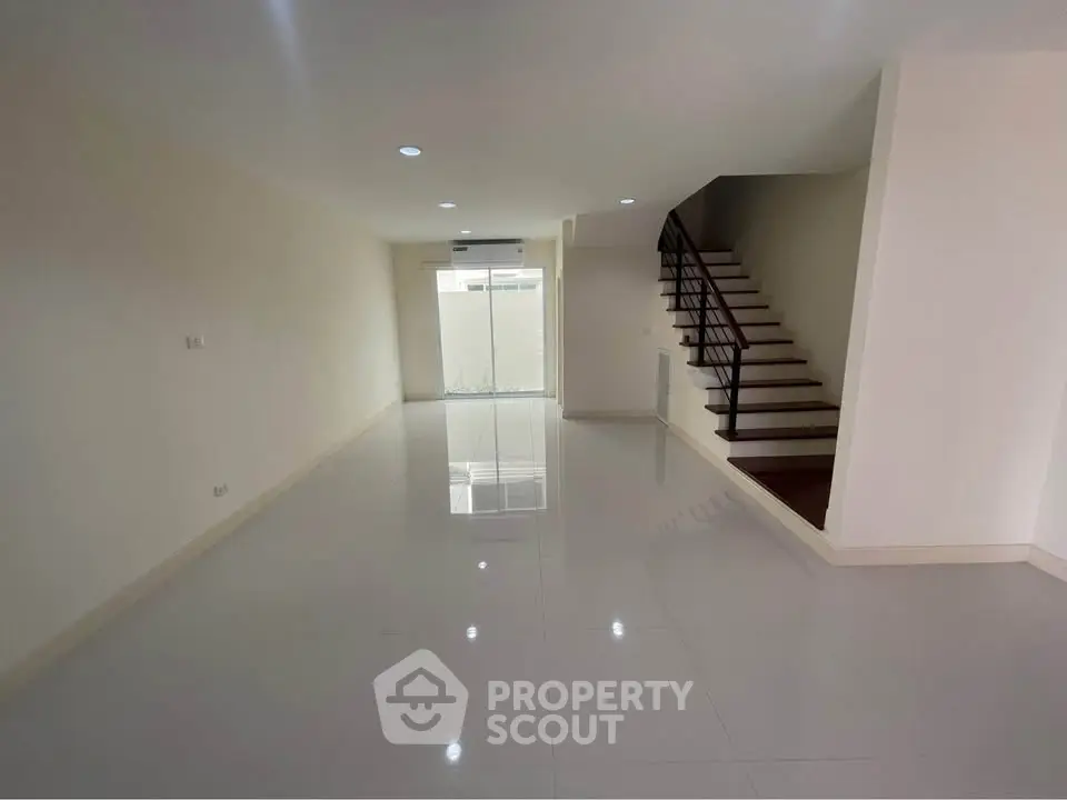 Spacious modern living room with sleek staircase and ample natural light
