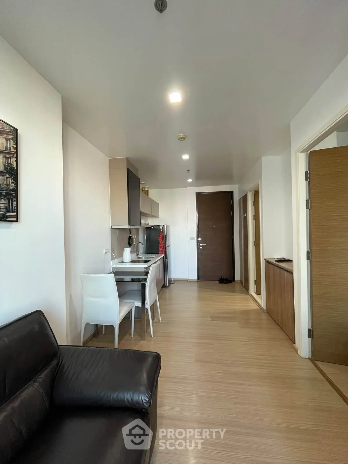Modern apartment interior with open kitchen and stylish living area, featuring sleek wooden flooring and contemporary decor.