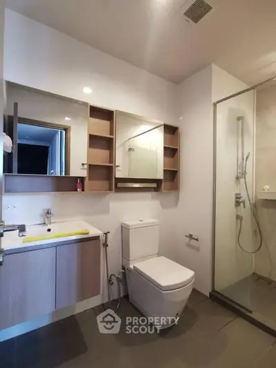Modern bathroom with glass shower and sleek vanity in contemporary apartment.