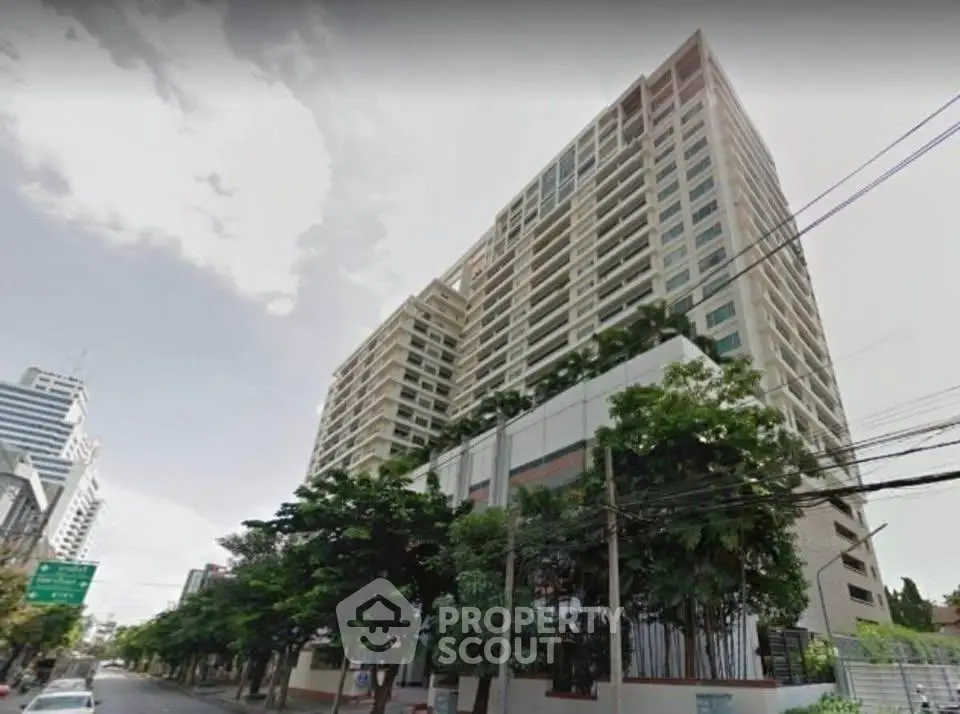 Modern high-rise building with lush greenery and urban street view.