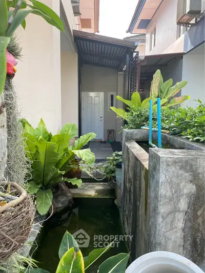 Charming garden entrance with lush greenery and serene water feature