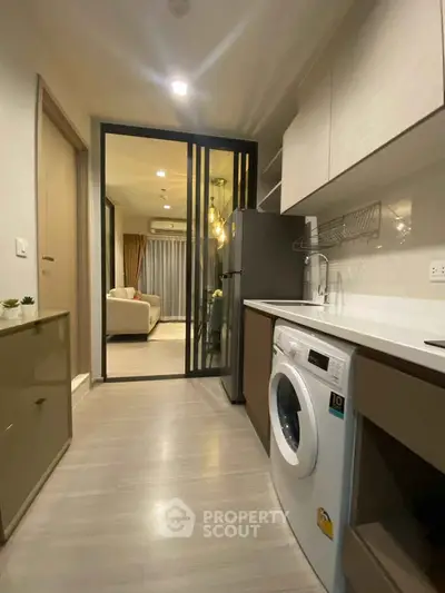 Modern kitchen with washing machine and open layout leading to living room