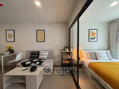 Modern studio apartment with stylish decor, featuring a cozy living area and a comfortable bed separated by glass partition.