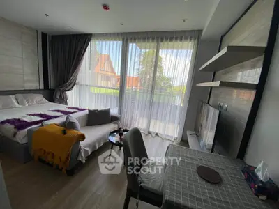 Modern bedroom with large windows and balcony view, featuring cozy decor and ample natural light.