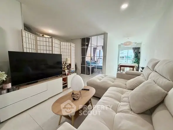 Spacious modern living room with plush seating and large TV, open to dining area.