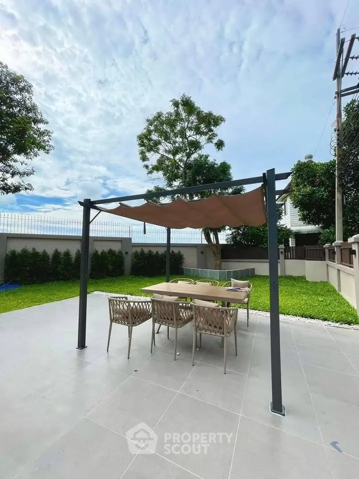 Spacious outdoor patio with modern pergola and dining set, perfect for entertaining in a lush garden setting.