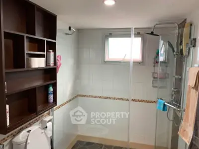 Modern bathroom with glass shower and wooden shelving, featuring sleek tile design.