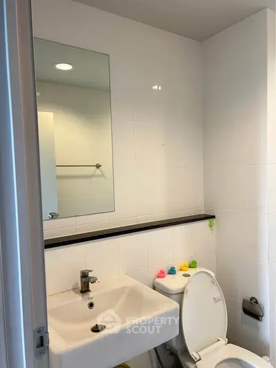 Modern bathroom with sleek white tiles and contemporary fixtures.