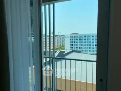 Modern apartment balcony with city view and clear blue sky.