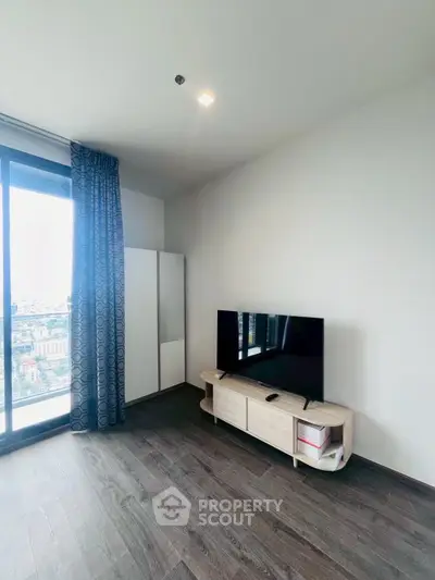 Modern living room with large window and stylish TV stand in high-rise apartment.