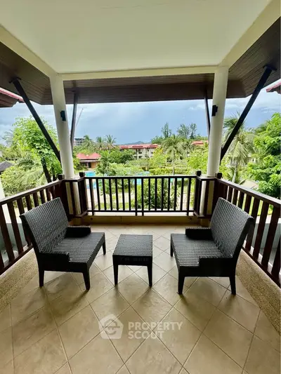 Spacious balcony with seating overlooking lush garden and pool view.