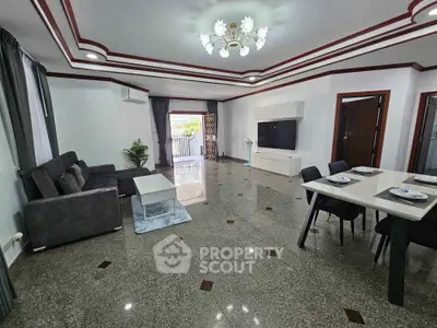 Spacious living room with modern decor and dining area, featuring elegant lighting and sleek furniture.