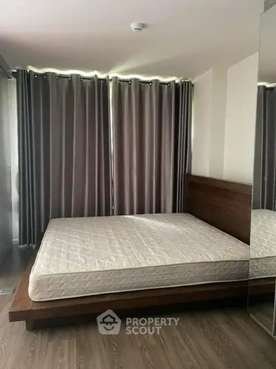 Spacious bedroom with wooden flooring and large windows for natural light.