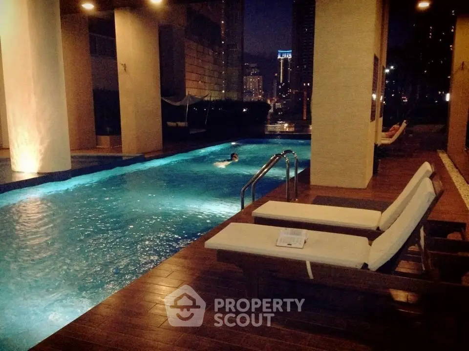 Luxurious night view of a serene swimming pool with lounge chairs in a high-rise setting.