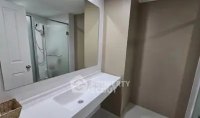 Modern bathroom with sleek sink and glass shower enclosure in contemporary home.
