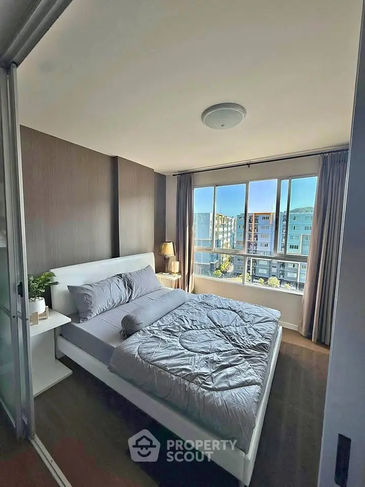 Modern bedroom with large window and city view, featuring sleek design and natural light.
