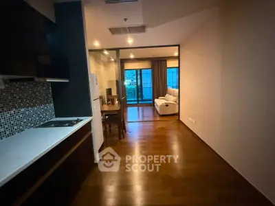 Spacious open-plan living area with modern kitchen and cozy seating, featuring elegant wooden flooring.
