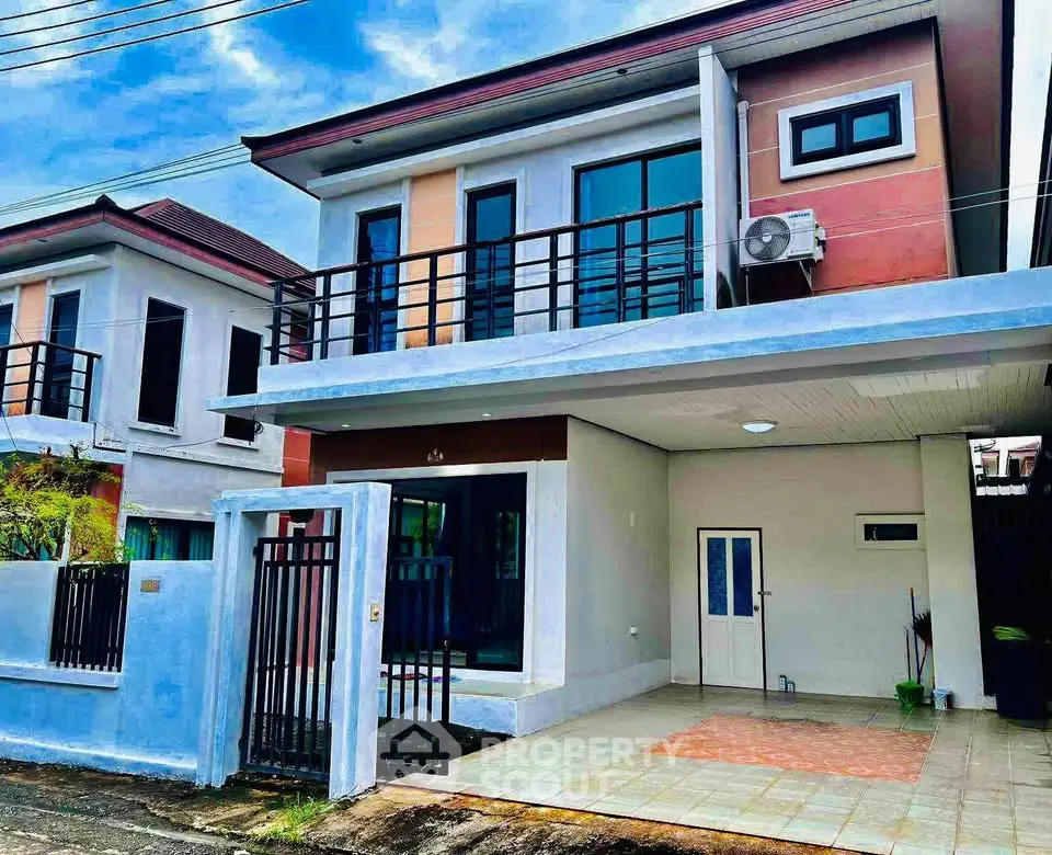 Modern two-story house with balcony and driveway in a suburban neighborhood.
