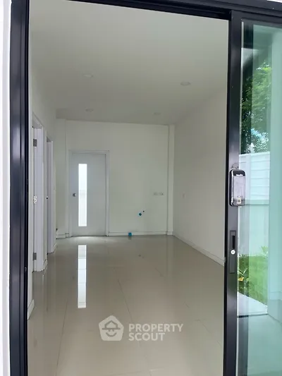 Spacious empty room with sliding glass door and glossy tile flooring