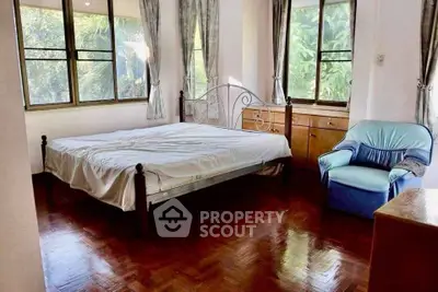 Spacious bedroom with large windows and wooden flooring in a serene setting.