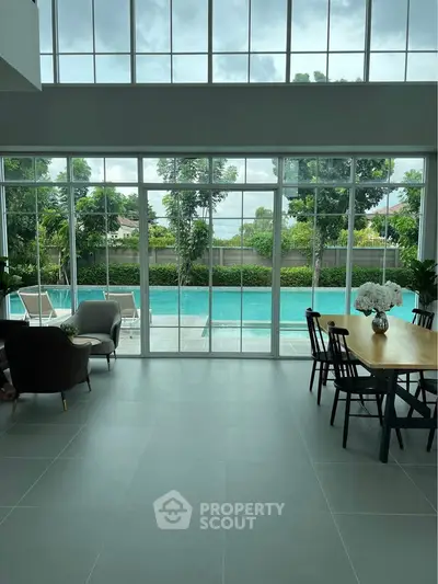 Luxurious living room with pool view, high ceilings, and elegant dining area, perfect for modern living.