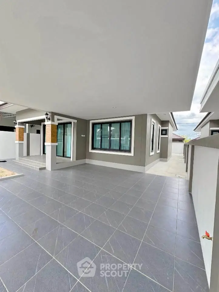 Spacious modern home exterior with sleek design and large tiled patio, perfect for outdoor living.