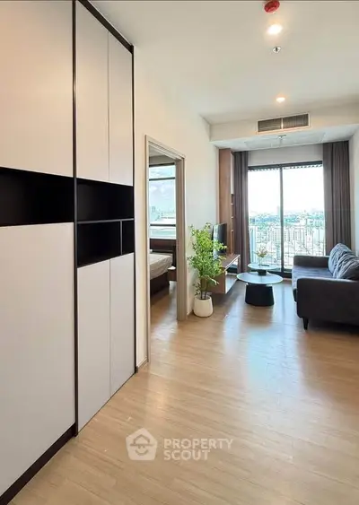 Modern living room with city view, stylish furniture, and natural light in a high-rise apartment.