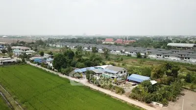 Aerial view of suburban houses surrounded by lush greenery and open fields.