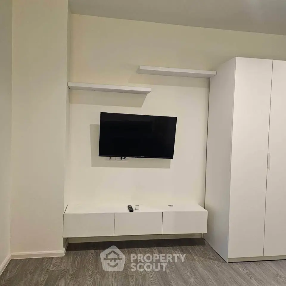 Modern living room with mounted TV and sleek white storage unit.