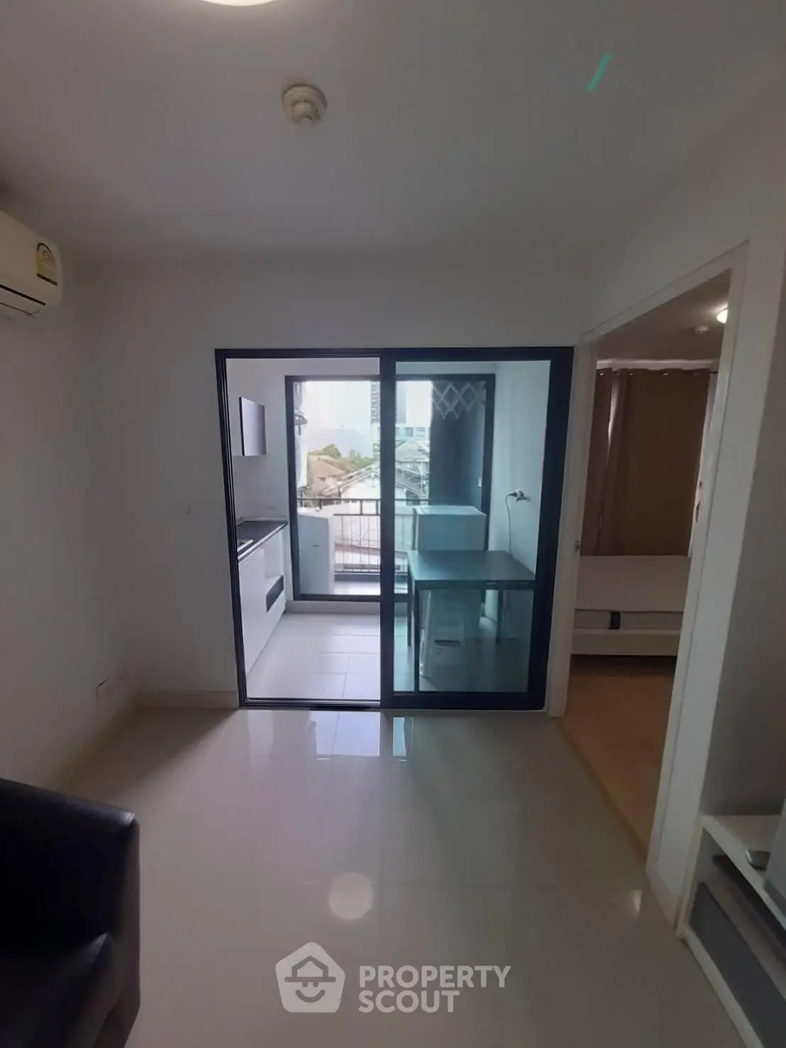 Modern apartment with glass sliding doors leading to a balcony, featuring a compact kitchen and cozy living space.