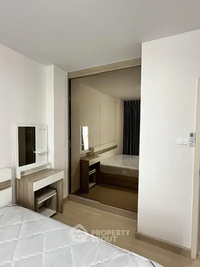 Modern bedroom with mirrored closet and stylish vanity in a sleek apartment.
