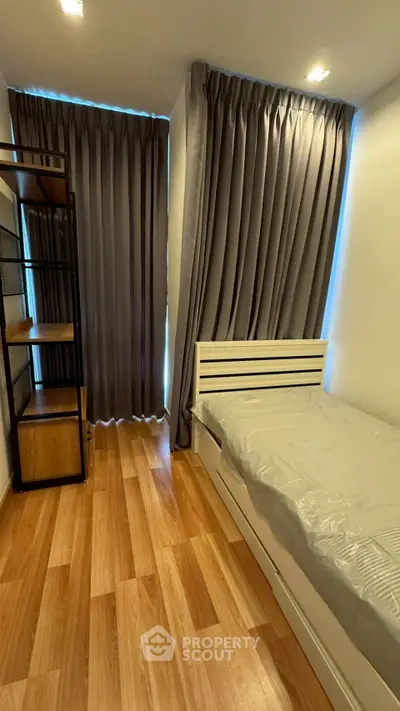 Cozy bedroom with wooden flooring and modern shelving, perfect for a minimalist lifestyle.