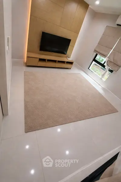 Modern living room with sleek TV setup and cozy carpet
