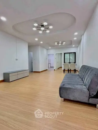 Spacious modern living room with stylish lighting and sleek furniture, perfect for contemporary living.