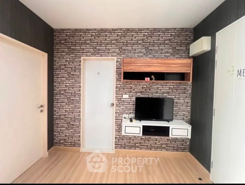 Modern living room with stylish brick accent wall and mounted TV unit.