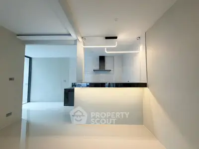Modern kitchen with sleek design and open layout, featuring contemporary lighting and glossy tiles.
