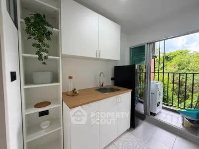 Modern kitchen with open layout and balcony view, featuring sleek cabinets and appliances.