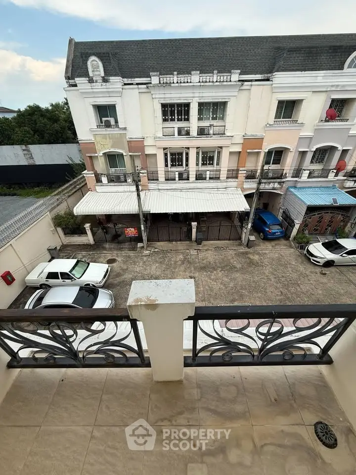 Charming balcony view overlooking a residential building and parking area, perfect for urban living.